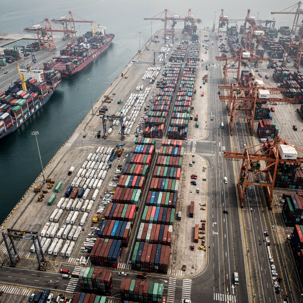Aerial view of a container terminal layout Top-down view of a busy container port terminal showing berths, cranes, yard stacks and truck lanes with clear separation; no text or logos